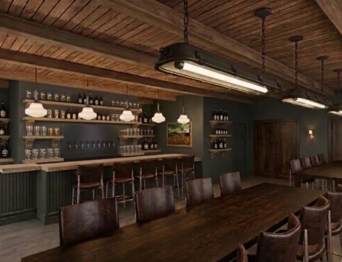 Rustic bar with wooden ceiling, shelves of bottles and glasses, a long bar counter, high chairs, and large wooden tables with brown leather chairs.
