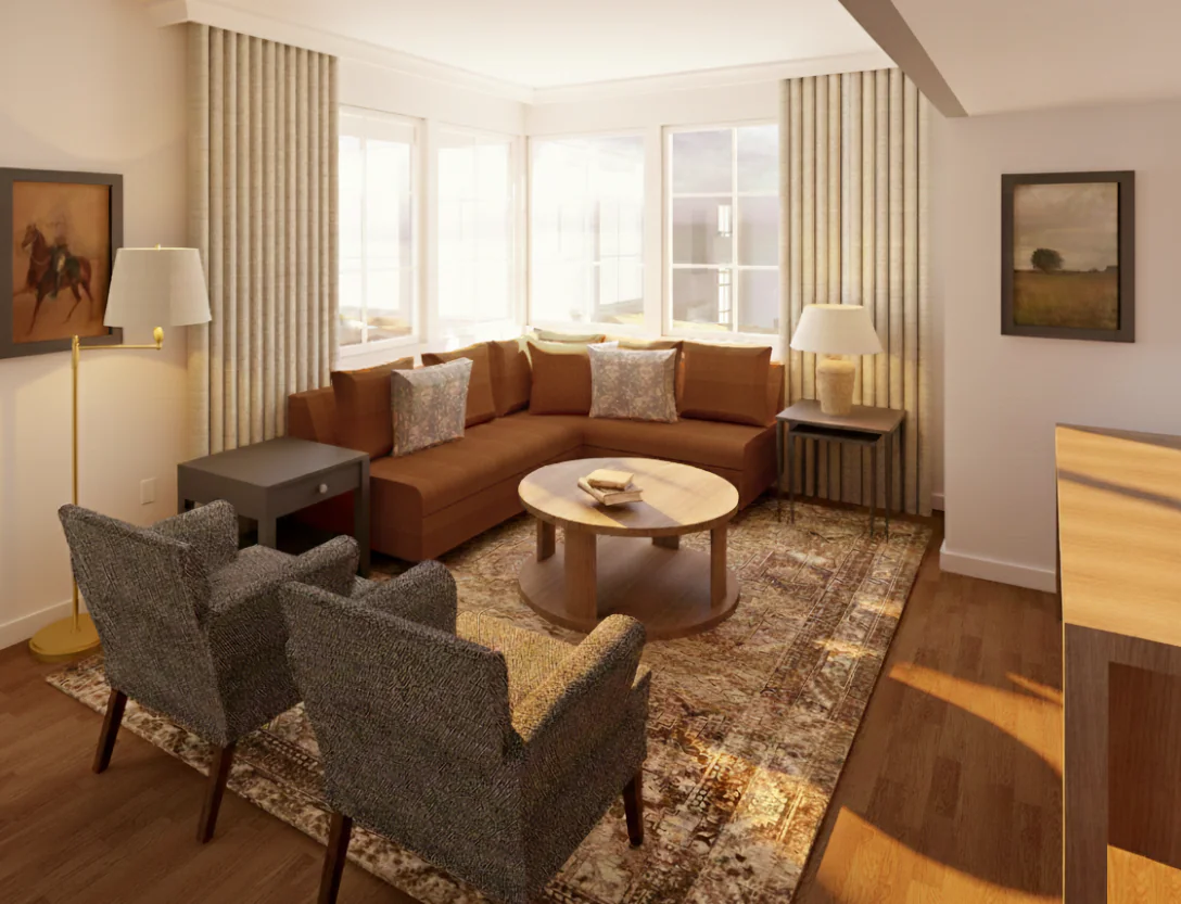 A cozy living room with a brown sectional sofa, two gray chairs, a round wooden coffee table, large windows, and framed art on the walls.